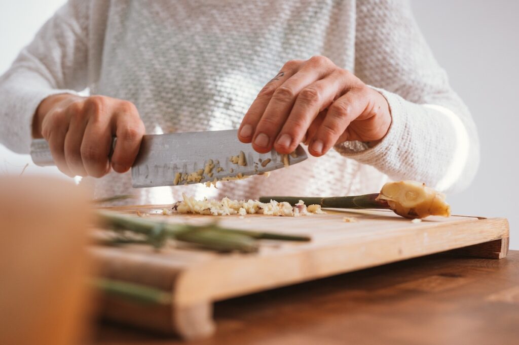 man chopping garlic on cutting board