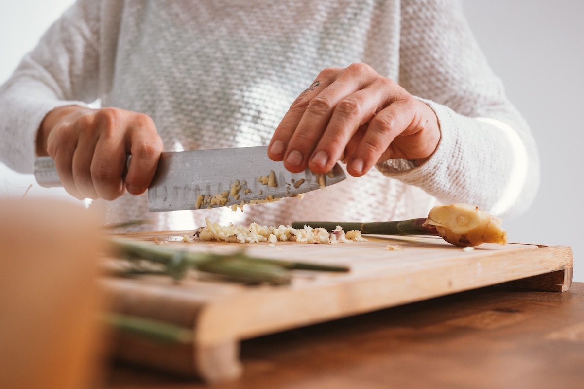 man chopping garlic on cutting board