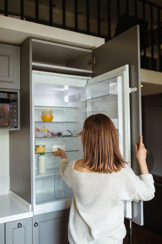 woman grabbing food from fridge